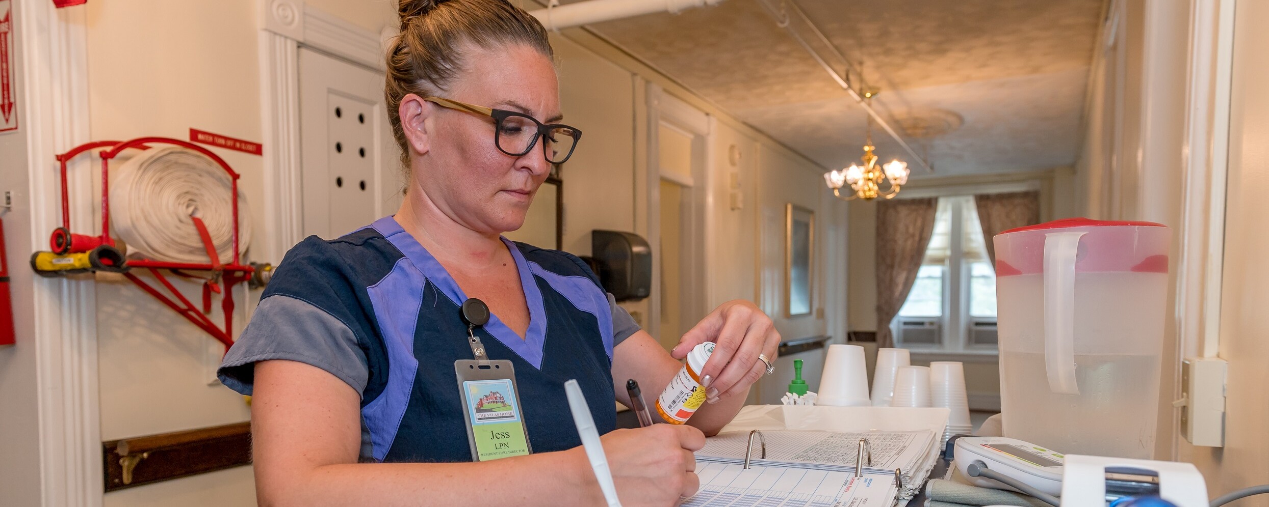 Female LPN reviewing medication before administering to a senior resident